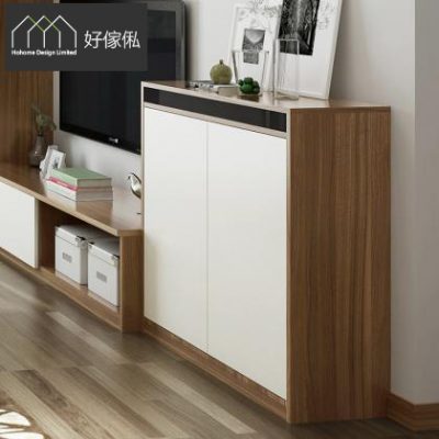 近鏡影住訂造電視櫃右邊嘅高身貯物櫃，啡木色框配白色雙門，櫃面擺住相架、花瓶同綠色擺設；左邊連住啡白矮電視櫃同開放層板，格內放兩個白色收納籃同書本，背景見到電視一角同淺色牆身，地下鋪深木紋地板。