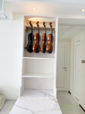 了垂直懸掛的收納方式，在近櫃頂的位置裝上木製的吊架，讓幾把小提琴可以整齊懸掛排列，這種收納既慳位，亦能展示小提琴本身優美的外觀