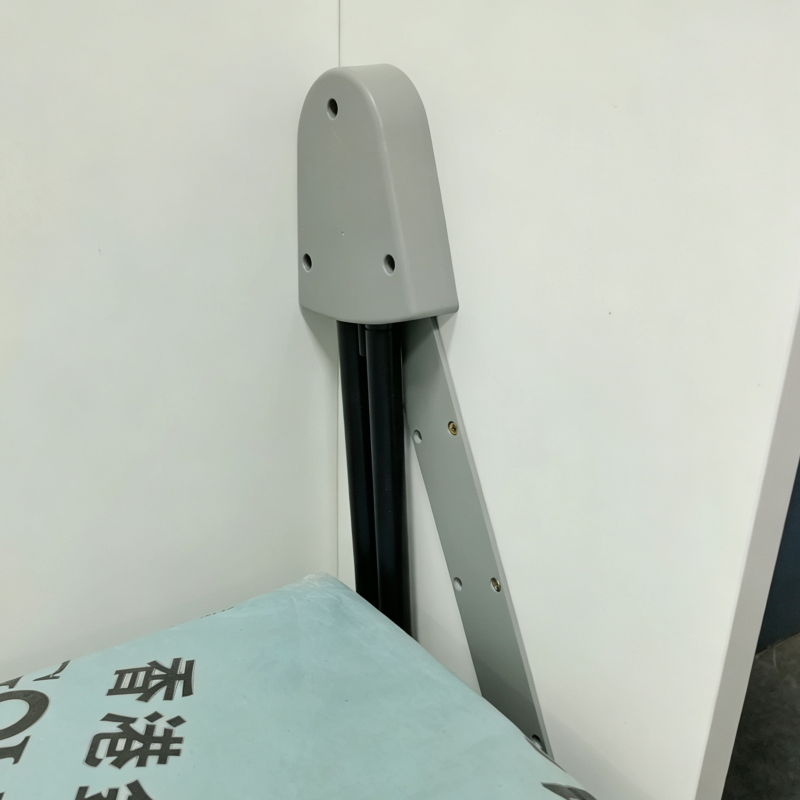 Livo直翻變形床內側結構近鏡，灰色金屬支撐臂固定在白色床箱上，旁邊可見黑色組件及淺藍色包裝床褥一角。