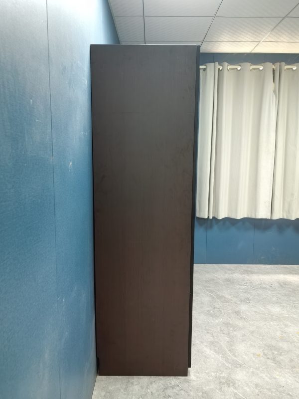 Wallace玻璃掩門衣櫃側面實拍圖，深啡近黑色木紋櫃身，靠淺藍色牆身擺放，背景見淺色窗簾同灰色地台，展廳環境。