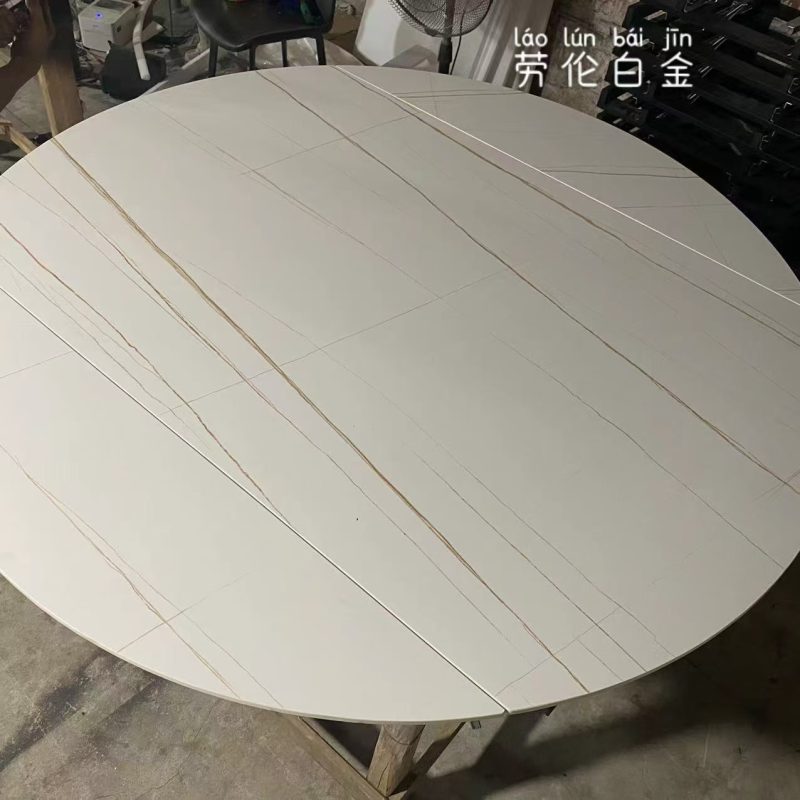 工場內俯拍啞光勞倫白金岩板圓餐枱，米白色枱面帶幼細金啡色斜紋及多道拼接線，圓形邊緣完整顯示整幅枱面花紋。