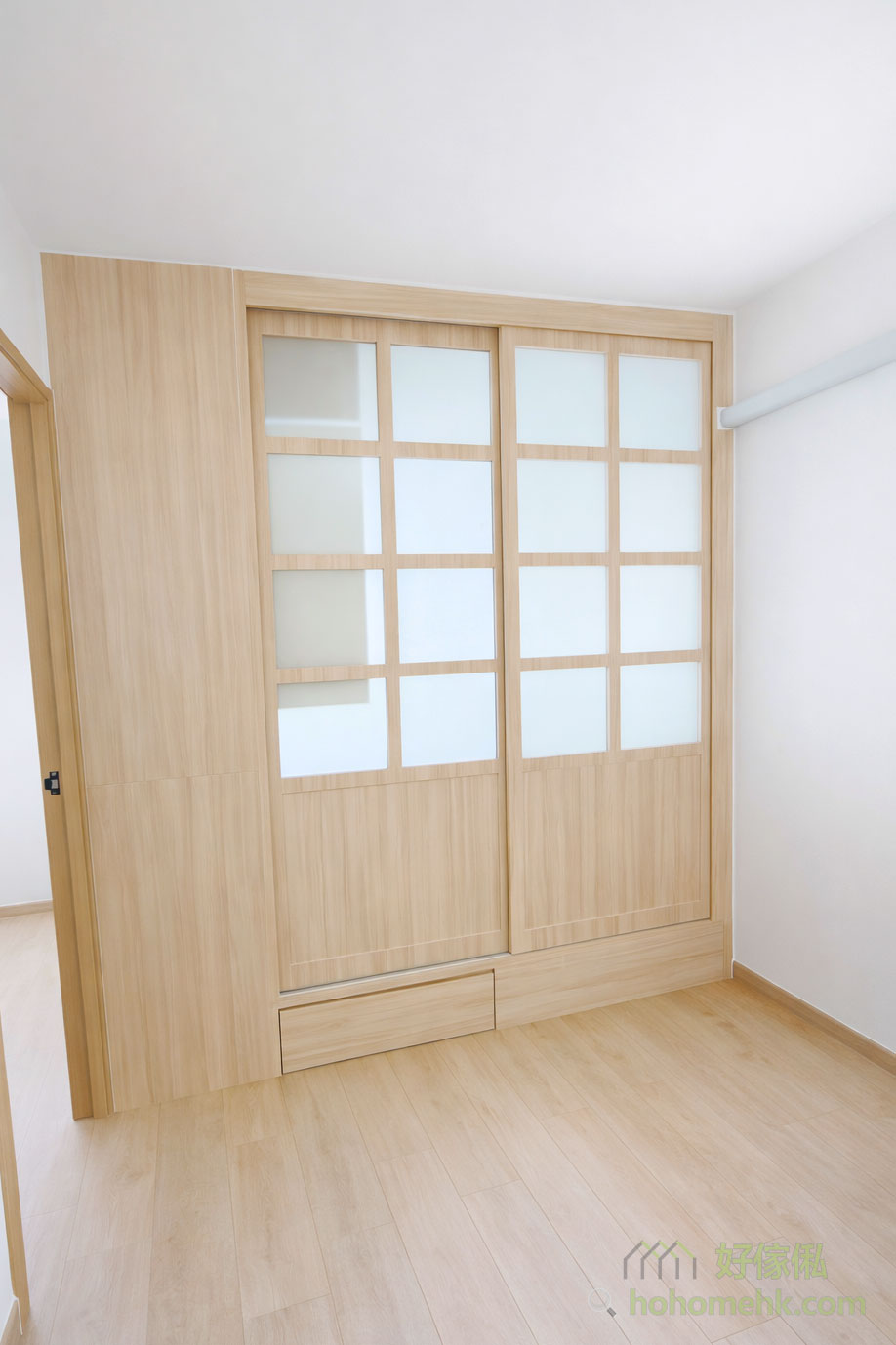 我們為客戶設計了一款日式趟門，上半部分採用木框磨砂玻璃，下半部分則為木板，令自然光可以穿透，為客廳帶來明亮感，同時保留房間的私密性，達到實用與美觀的平衡。