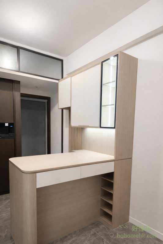 在深水埗Belgravia Place的全屋傢俬設計中，中島櫃的加入成為了空間劃分的關鍵角色。這個半高中島櫃與C字櫃無縫連接，不僅提供額外的儲物空間，還可以作為餐桌使用，滿足日常用餐需求。同時，它巧妙地分隔了門口與客廳的區域，讓整體空間更有層次感，實現了功能與美觀的雙贏。