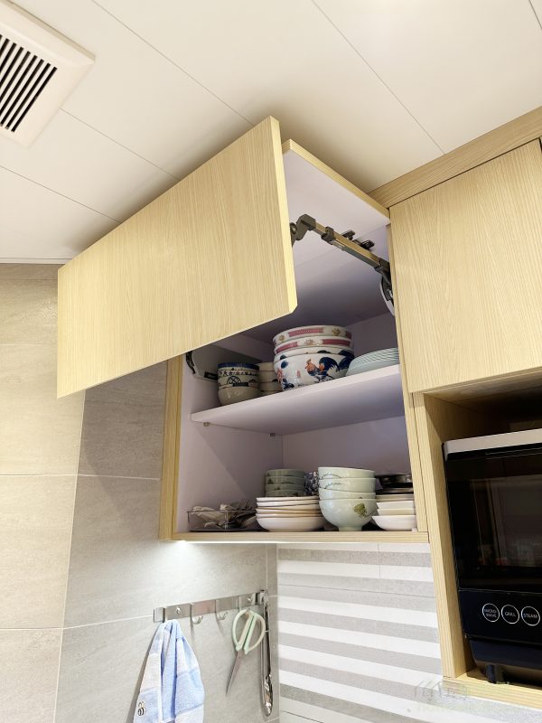 吊櫃的設計同樣考慮到實用性和安全性，採用了上翻門設計，開門時不會撞到頭，使用更加方便。同時，吊櫃內部空間充足，可以存放碗碟、乾糧等日常用品，令廚房保持整潔。這樣的設計不僅解決了空間利用問題，更提升了居家生活的便利性。