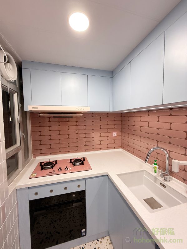 這個廚房設計以客戶的馬卡龍主題為靈感，採用天藍色焗漆作為地櫃和吊櫃的主色調，營造出充滿童話感的空間。每個細節都經過精心處理，所有收口條和櫃腳擋板都做到無色差，讓整體效果更加和諧美觀。再配上客戶精心挑選的粉紅色煮食爐，色彩碰撞之間呈現出獨特的視覺效果，令人耳目一新。