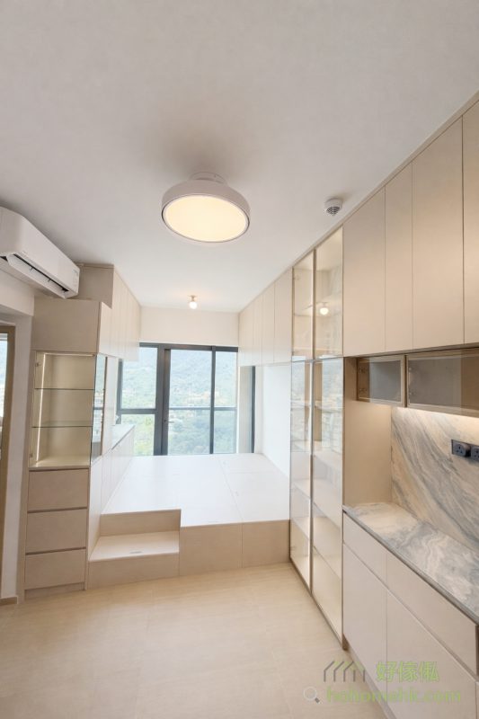 長方形開則的客廳，可以透過訂造地台將客飯廳自然分區。地台設計不僅能提供額外儲物空間，其出色的承重力更能承托梳化等大型家具。同時，地台的高度令電視櫃實現「做到頂」的設計，最大化利用牆面空間，而梳化上方的吊櫃也變得方便拿取，賦予生活更多便利。