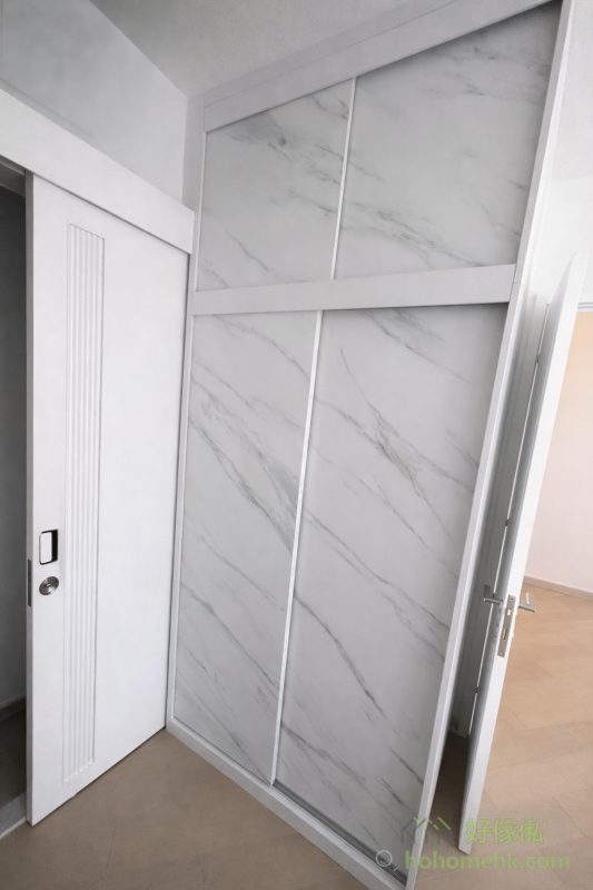 房內的衣櫃亦沿用電視櫃及背景牆的板材及紋理，確保全屋設計風格一致。大理石紋的衣櫃簡約時尚，實用之餘更顯生活品味。這種設計不僅耐看，亦符合現代人對簡約生活的追求。女