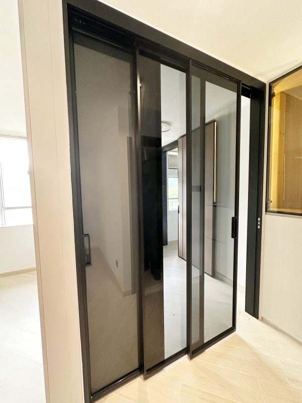 黑色玻璃趟門既時尚又實用。穿過趟門後延伸出一排長間隔櫃，大大增加了儲物靈活性。不僅提升生活舒適度，更成功融入現代極簡風格。