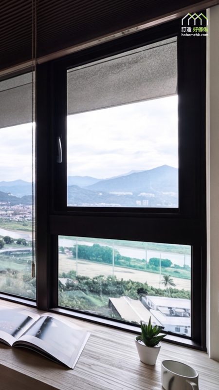 黑框大窗外望山巒及開揚景觀，室內以木紋長枱面沿窗台設置工作位，枱上擺有攤開嘅書本、小盆栽與白色杯，深色百葉簾收於頂部。