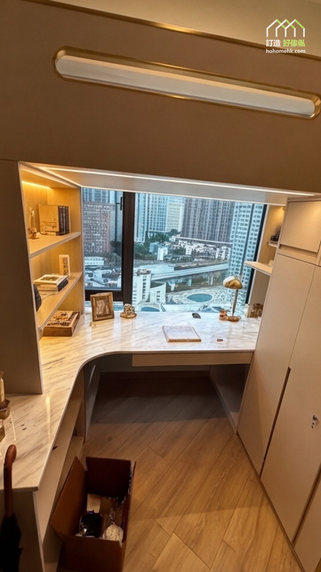 窗前白灰雲石紋轉角書枱由兩側延伸，中間留出座位，上方可見組合床暖灰圍板，左右暖木書架以燈帶照亮書本飾物。