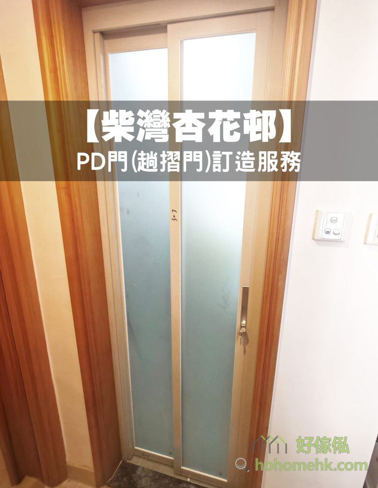 柴灣杏花邨住宅走廊內，浴室門口裝上銀色金屬框PD趟摺門，兩幅藍灰色半透明磨砂門板閉合於木色門框內，右側設長形拉手及門鎖，旁邊白牆有兩組開關。